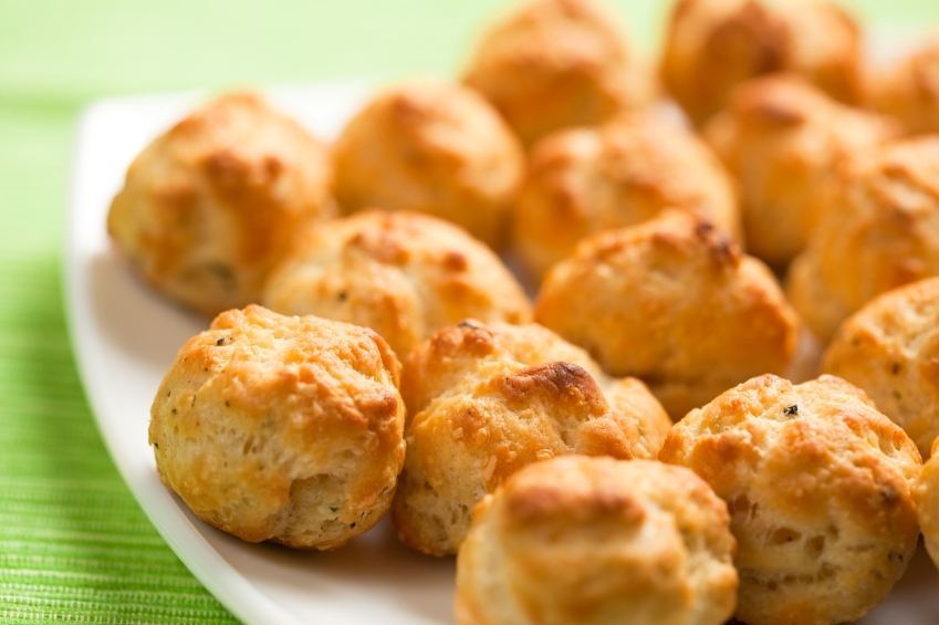 Gougeres, tiny French cheese buns, on a white plate.